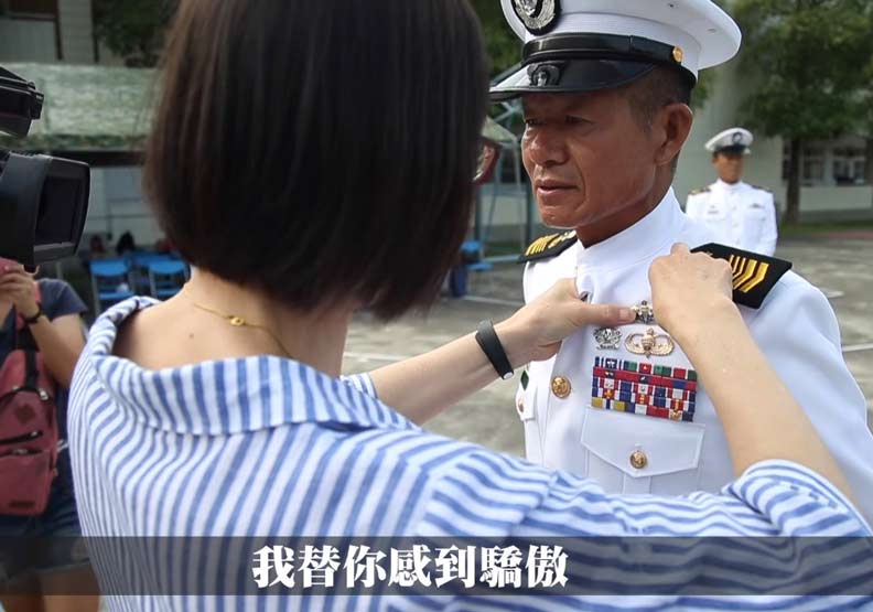 何朝明的太太為他繫上徽章，恭喜他完成水中爆破專長班的挑戰。圖取自國防部發言人