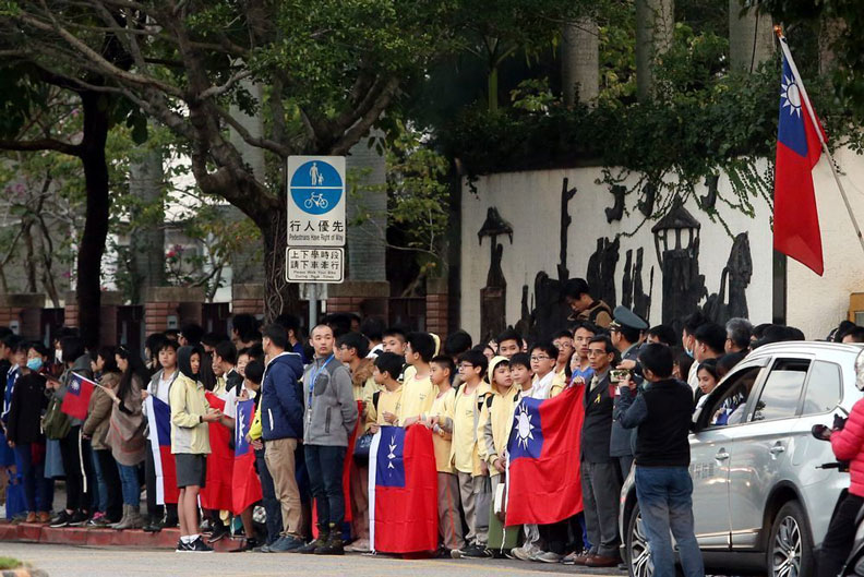 空難官兵葬禮車隊經過,沿途不少學生手持國旗在路邊致意。聯合新聞網提供