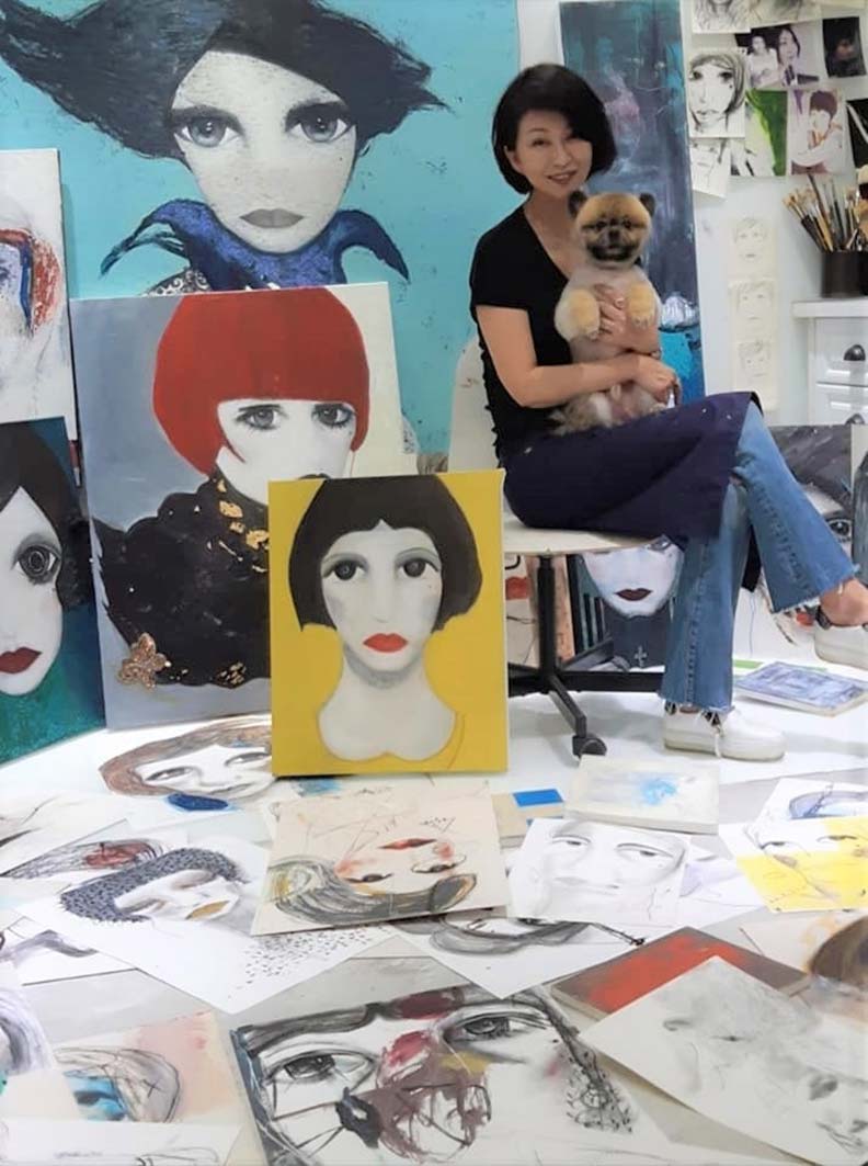 楊林的工作室裡,約有60多幅畫同時進行,圖中的她抱著愛犬「以勒」。(楊林提供)