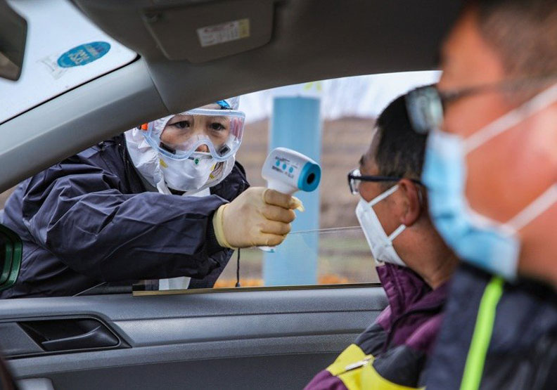 山東榮成疾控中心人員對進城車輛的駕駛人員及乘客，檢測體溫。新華社