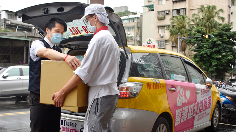 台灣大車隊的愛心司機和開平餐飲學校的學生們協力,將要送給醫護人員們的暖心餐盒,小心翼翼地搬運上車以確保送餐品質。