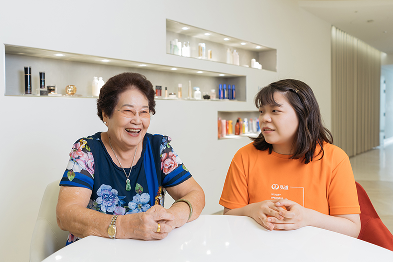 弘道基金會南港據點社區輔導員王敬文（右）陪伴賴葉員奶奶，分享化妝保養課程的趣味樂事。