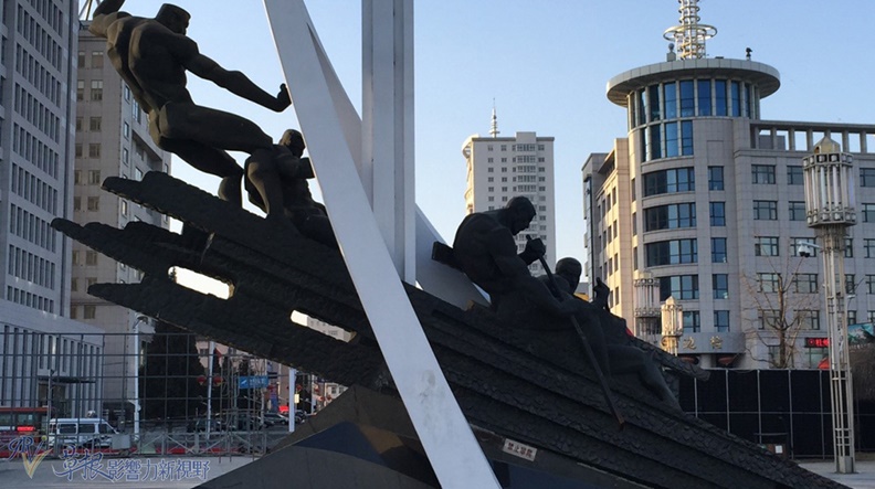 友誼前堤岸上的英勇奮鬥雕塑,後方可見丹東繁榮的市區。