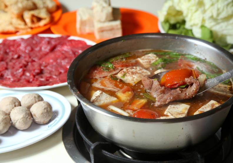 西市汕頭館沙茶牛肉火鍋，大蔥與番茄漂浮著，牛肉丸、豆腐在湯中沸煮，讓人食指大動。