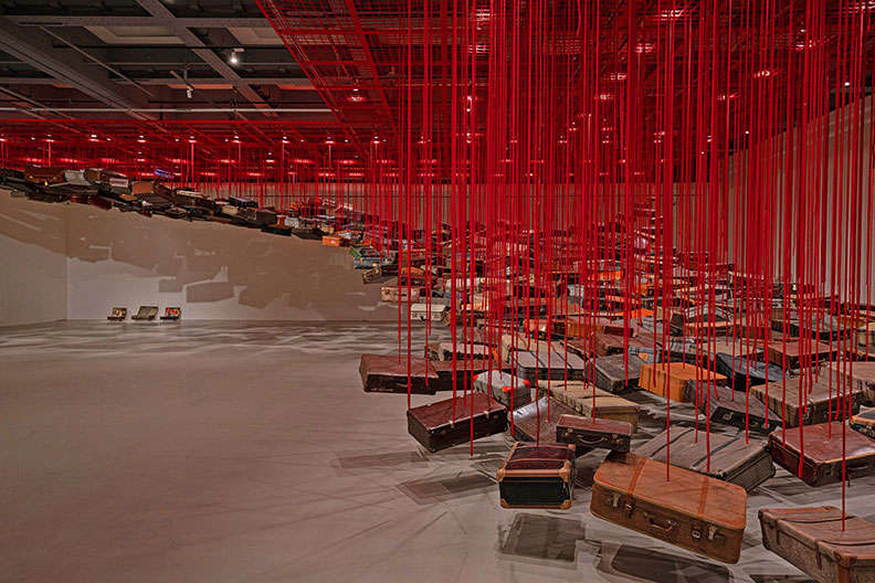 塩田千春,《集聚—找尋目的地》,2014/2021,行李箱、馬達、紅繩,尺寸依空間而定。取自臺北市立美術館。