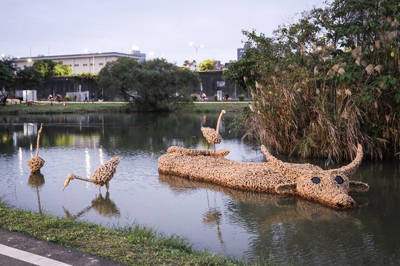 新北濕地藝術季在板橋區新月橋下的新海二期人工濕地登場,展出14件取自濕地素材的創作品,展出到2/9,是年節出遊的好所在。圖為稻草編織水牛在水中打滾的「牛汶水」。